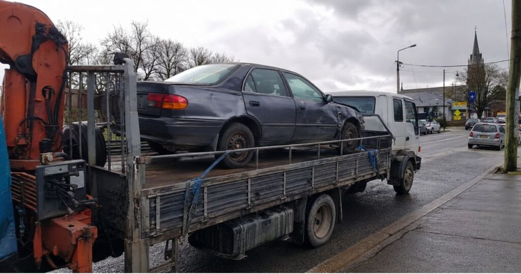 Scrap cars loaded on a flatbed truck for removal in Dunedin